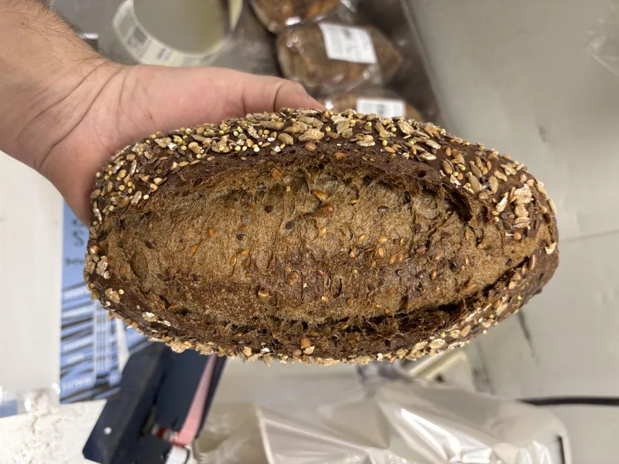 Pain au blé malté torréfié, coupé, tenu en main